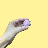 Bonbon de bain, mini bombe de bain mauve ou violet dans une main