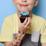 Tatouages petits gateaux de Pico Tatoo sur le bras d'un jeune garçon qui mange un muffin