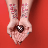 Tatouages Saint Valentin de Pico Tatoo Coeur Lettre Amoureux. Mains avec petit coeurs en chocolat avec bras tatoués.